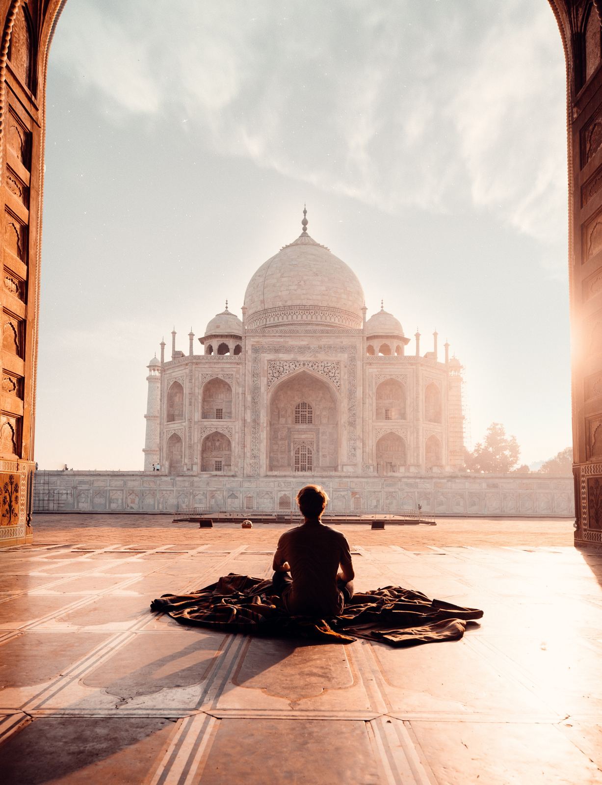 Traveller sitting before the Taj Mahal at sunrise